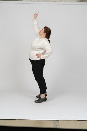 Side view of a plus size woman in casual clothes standing with raised arm