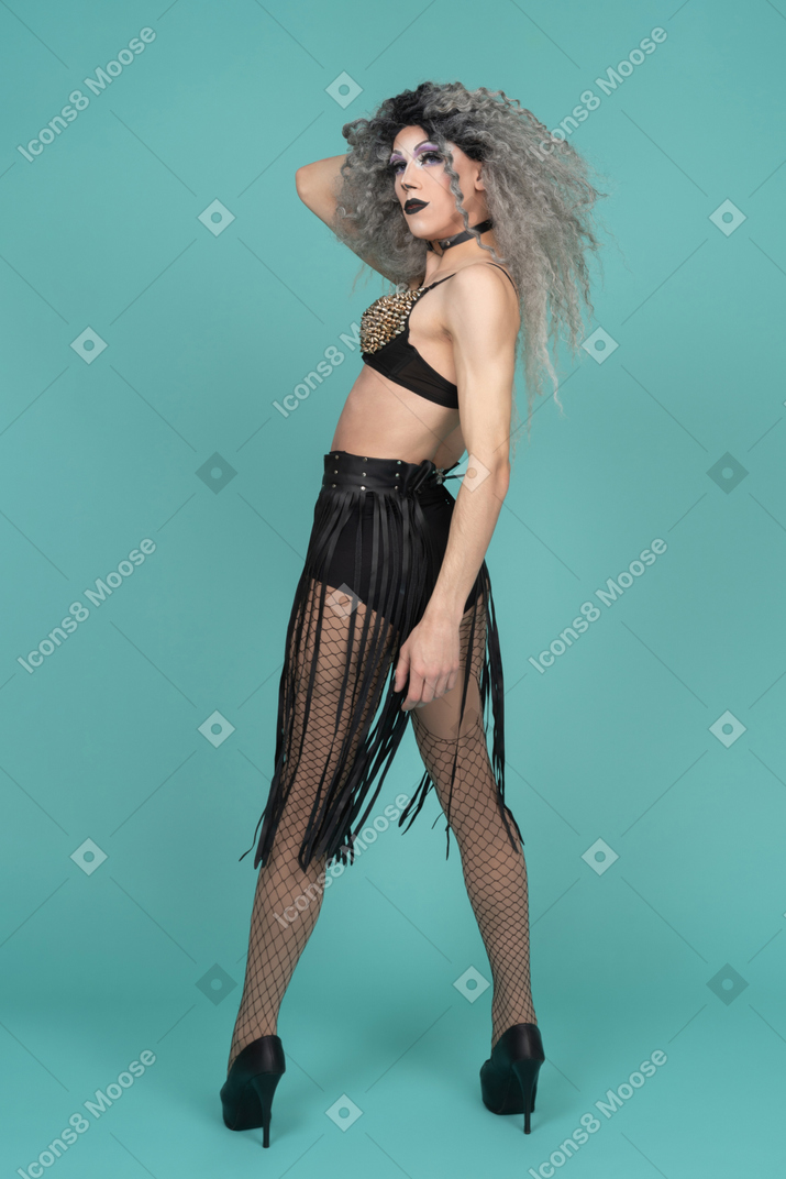Drag queen in all black outfit standing half turned