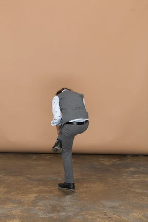 Rear view of a boy in suit standing on one leg