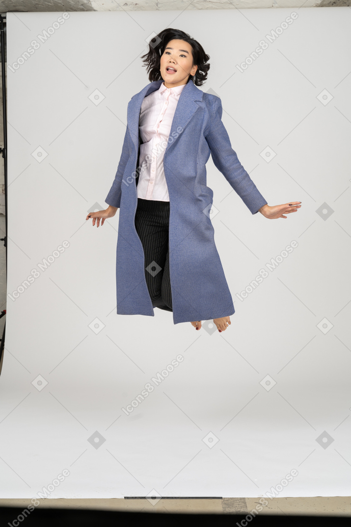 Business woman in coat jumping