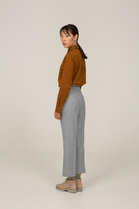 Vista posteriore di tre quarti di una giovane donna asiatica in calzoni e camicetta che si gira dall'altra parte