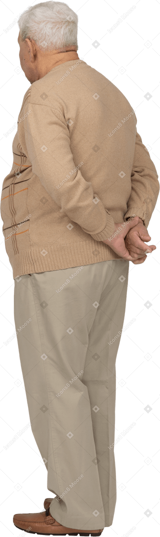 後ろ手で立っているカジュアルな服装の老人の側面図