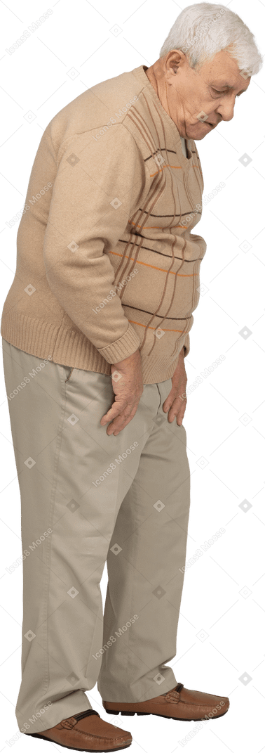 Vista lateral de un anciano con ropa informal mirando hacia abajo