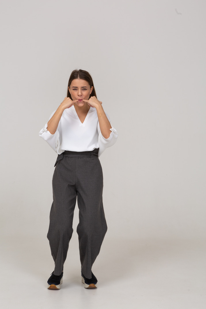 Front view of a whistling young lady in office clothing leaning forward