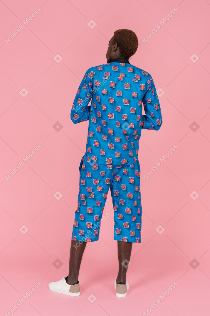Black man in blue pajamas standing on the pink background