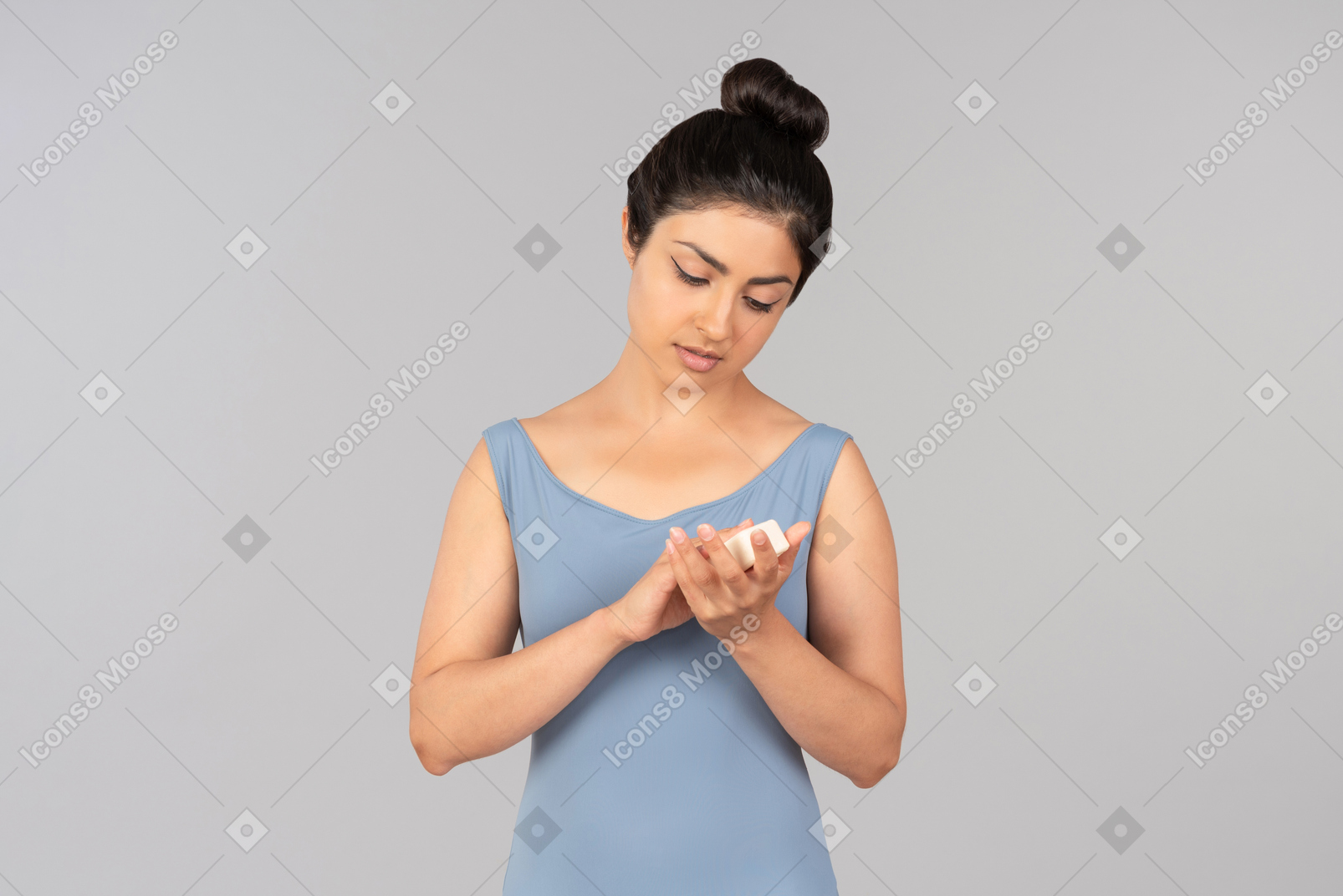 Young indian woman looking at cream bottle she's holding