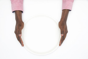 Black male hands holding empty white plate