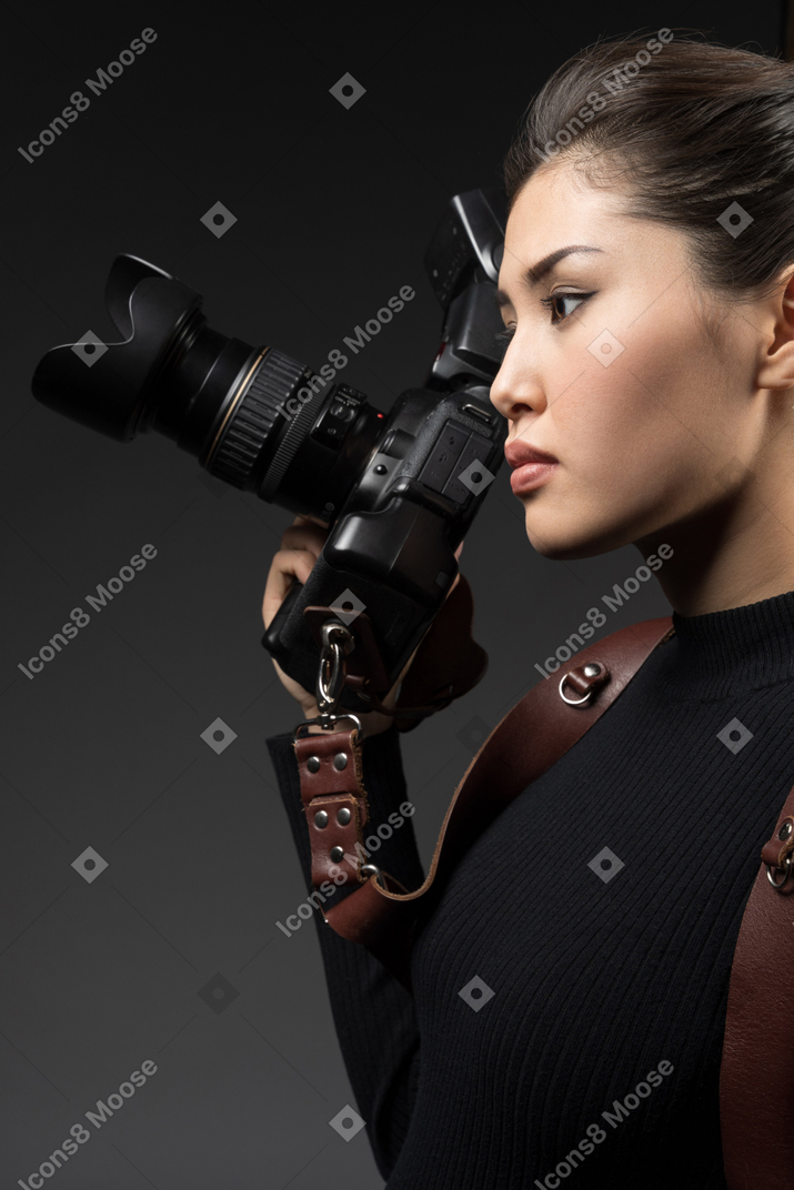 Young woman holding a camera and looking sideways