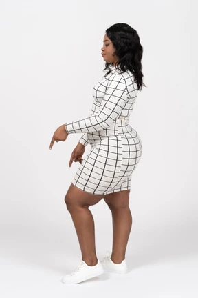 Side view of a beautiful young woman in casual clothes pointing down with a finger