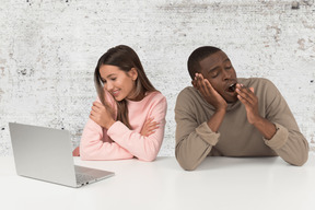 A man and a woman sitting in front of a laptop