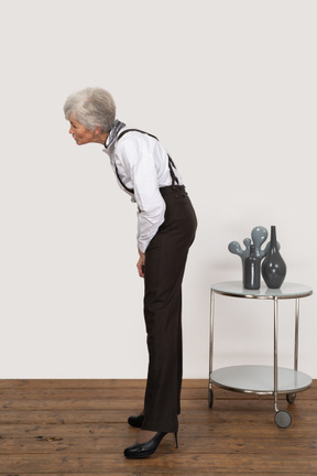 Side view of a curious old lady in office clothing leaning forward