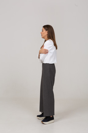 Vista lateral de uma jovem preocupada com roupas de escritório, cruzando os braços