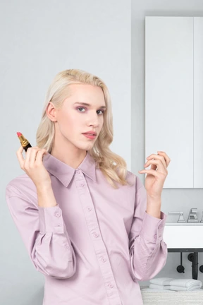 A woman in a pink shirt holding a lipstick