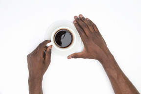 Black male hands holding cup of black coffee