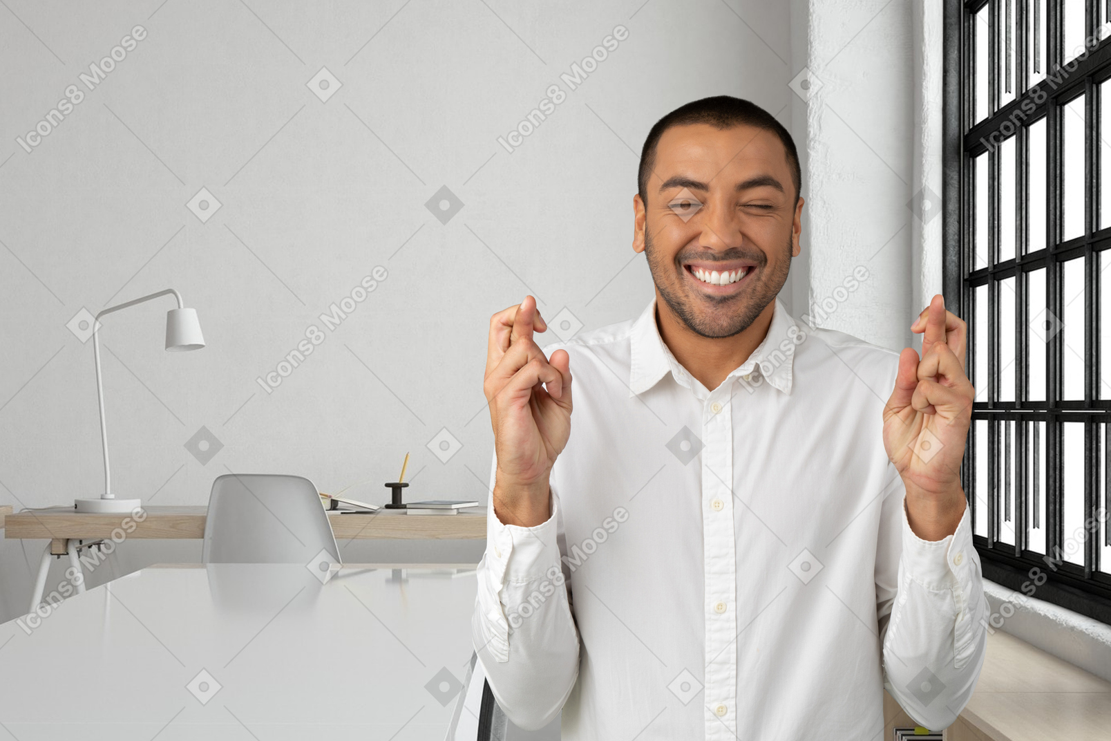 A smiling man crossing his fingers in an office