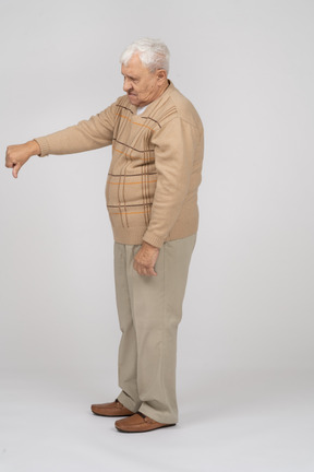 Vista laterale di un vecchio in abiti casual che mostra il pollice verso il basso