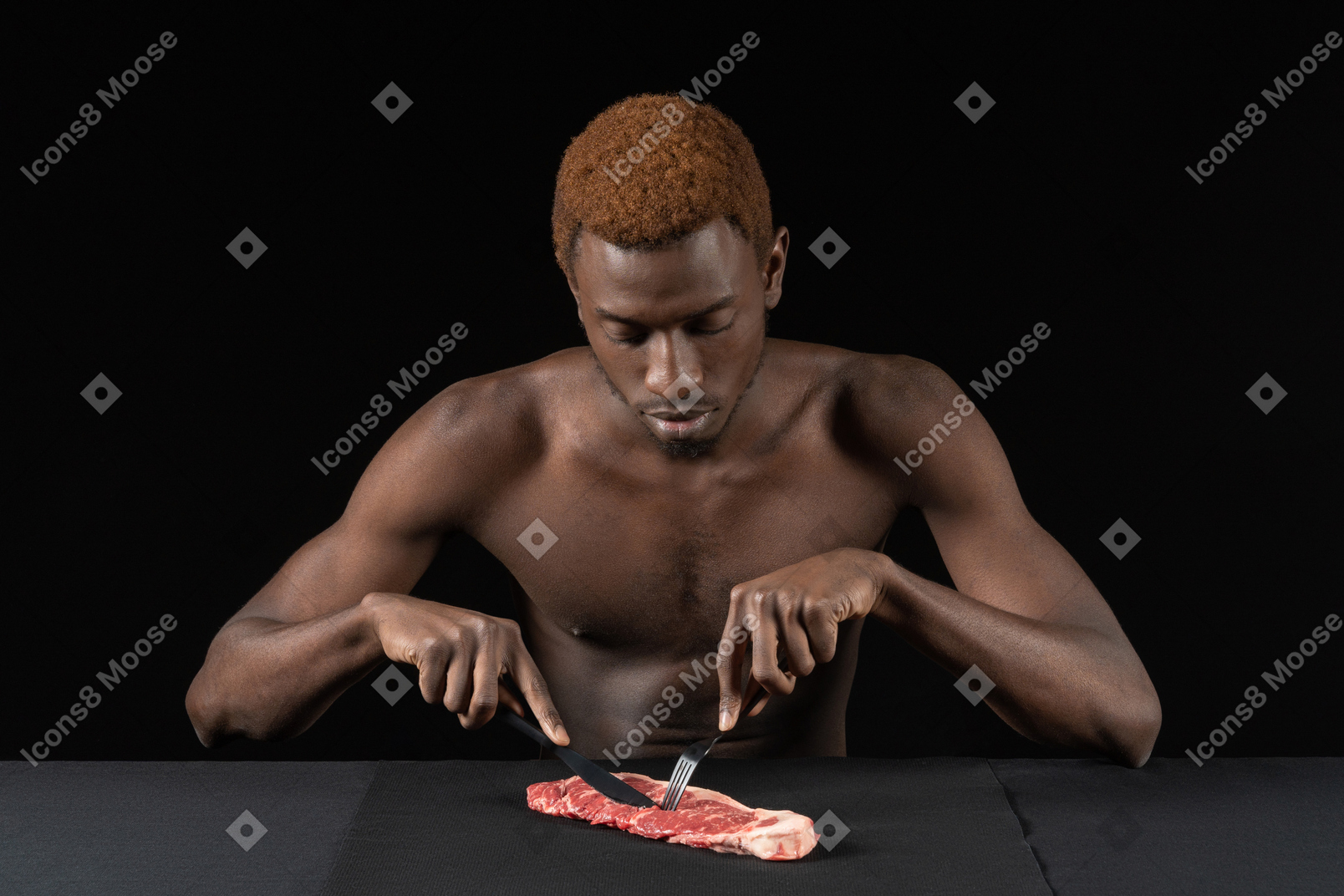 Front view of a young afro man cutting meat