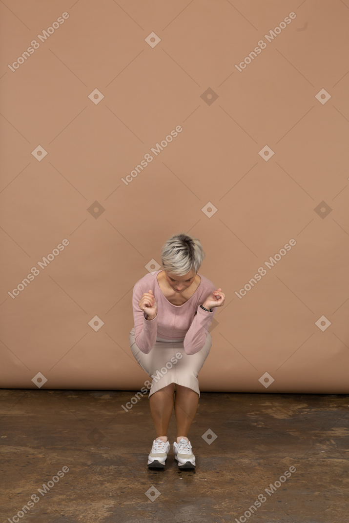 Женщина, сидящая на корточках, вид спереди
