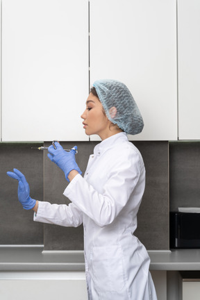 A woman in a white coat and blue gloves