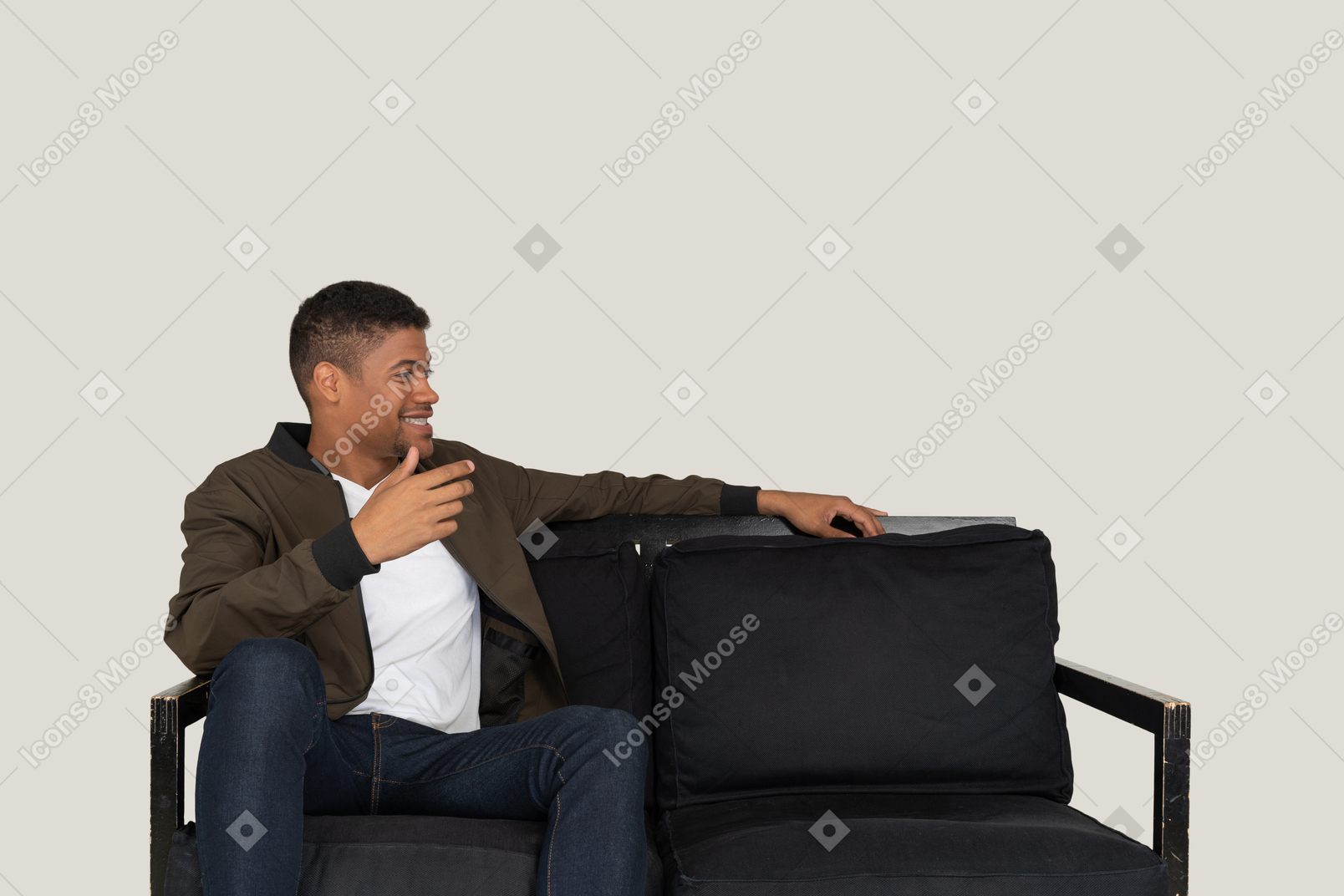 Smiling young man sitting on the sofa and telling something