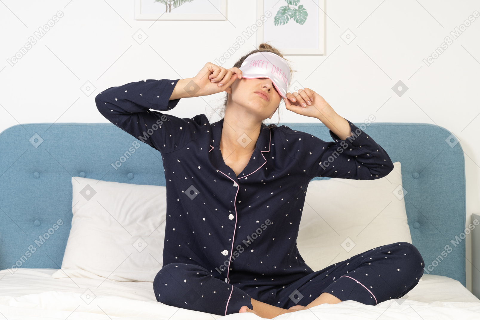 Front view of a young lady in pajamas putting on sleeping mask