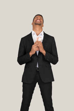 Vorderansicht eines jungen mannes im schwarzen anzug mit banknoten
