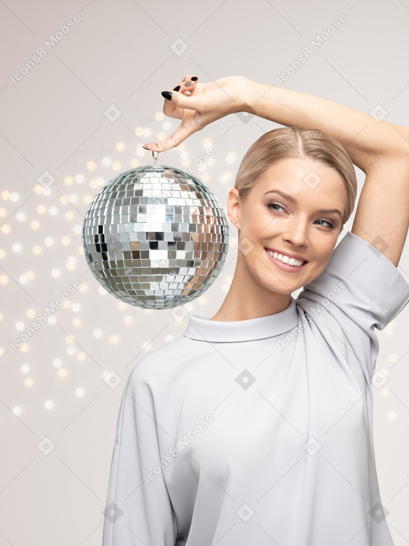 Young woman holding disco ball during christmas party