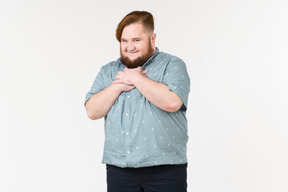 A fat man smiling shyly with his hands on his chest