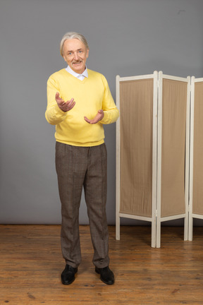 Front view of an old smiling man explaining something while gesticulating