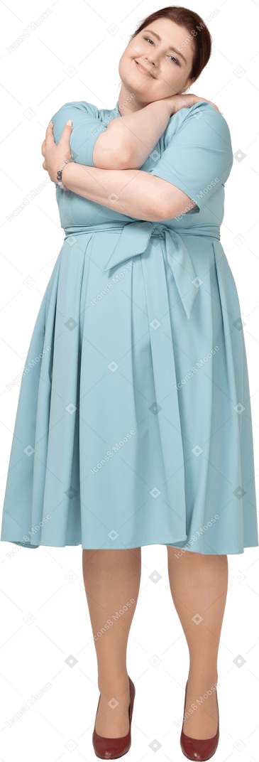一个穿着蓝色连衣裙的女人拥抱自己的前视图