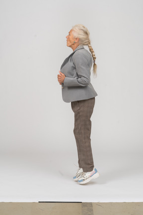 Side view of an old lady in suit jumping