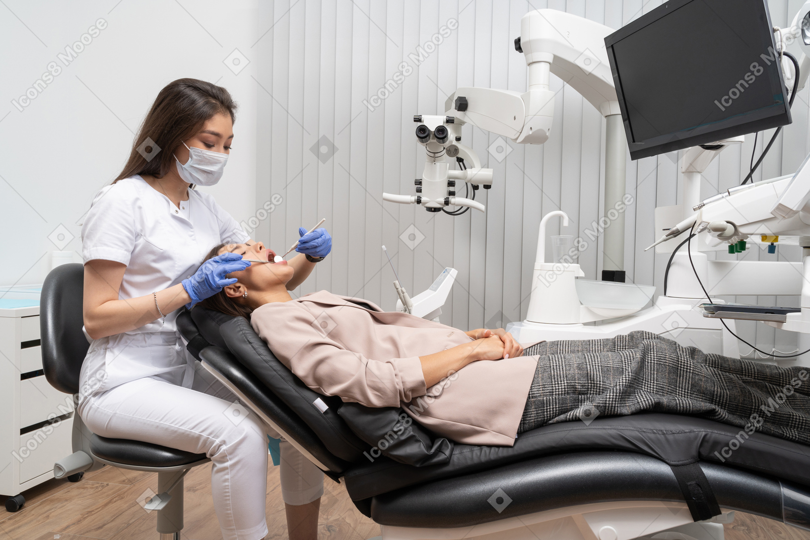 거울로 그녀의 환자를 검사하는 여성 치과 의사의 전체 길이
