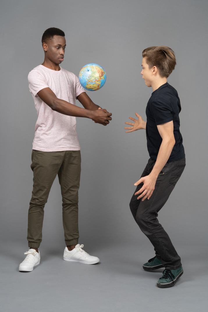 Two young men playing volleyball using the earth mini globe