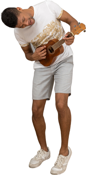Visão de três quartos de um homem inclinado para a frente e tocando ukulele animadamente