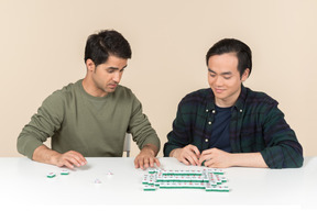 Interracial friends sitting at the table and playing board game