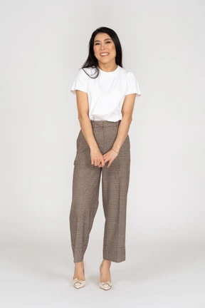Front view of a shy smiling young lady in breeches and t-shirt holding hands together
