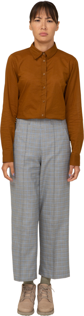 Vista frontal de una joven asiática desconcertada en calzones y blusa inmóvil