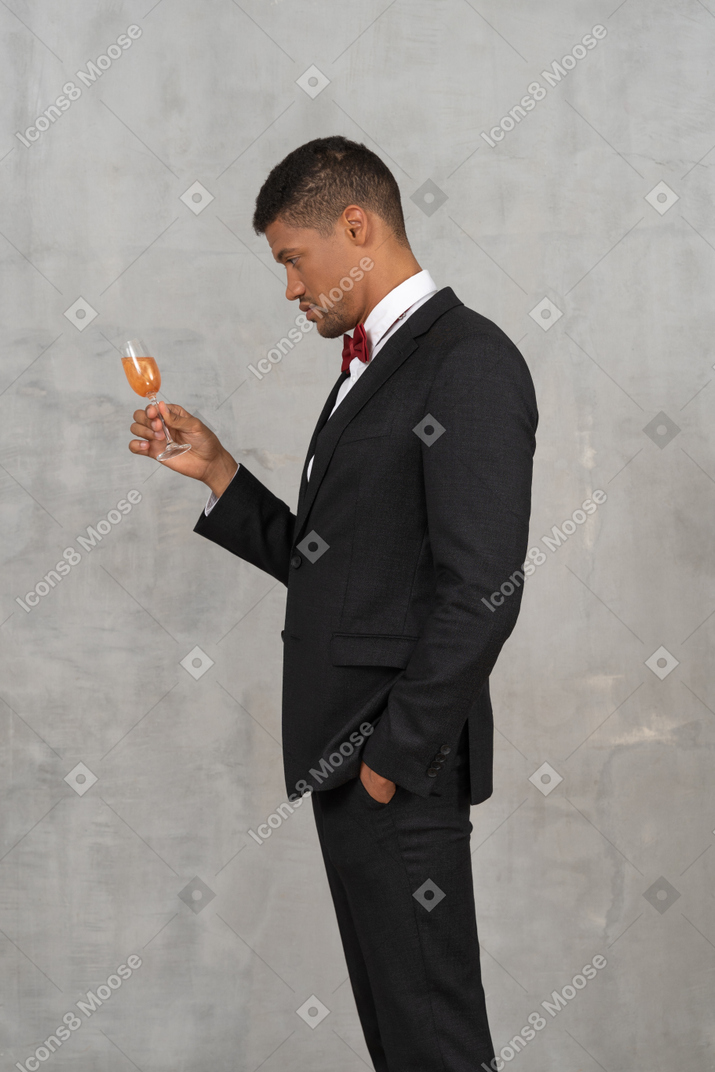 Вид сбоку молодого человека, смотрящего на бокал шампанского