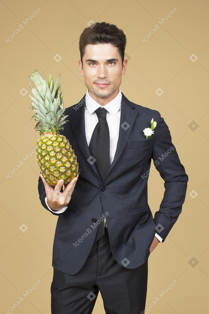 Marié en costume de mariage tenant un ananas