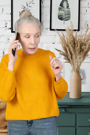 A woman in a yellow sweater talking on a cell phone