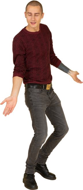 Вид в три четверти молодого человека в красном пуловере, стоящего с широко расставленными руками и ногами