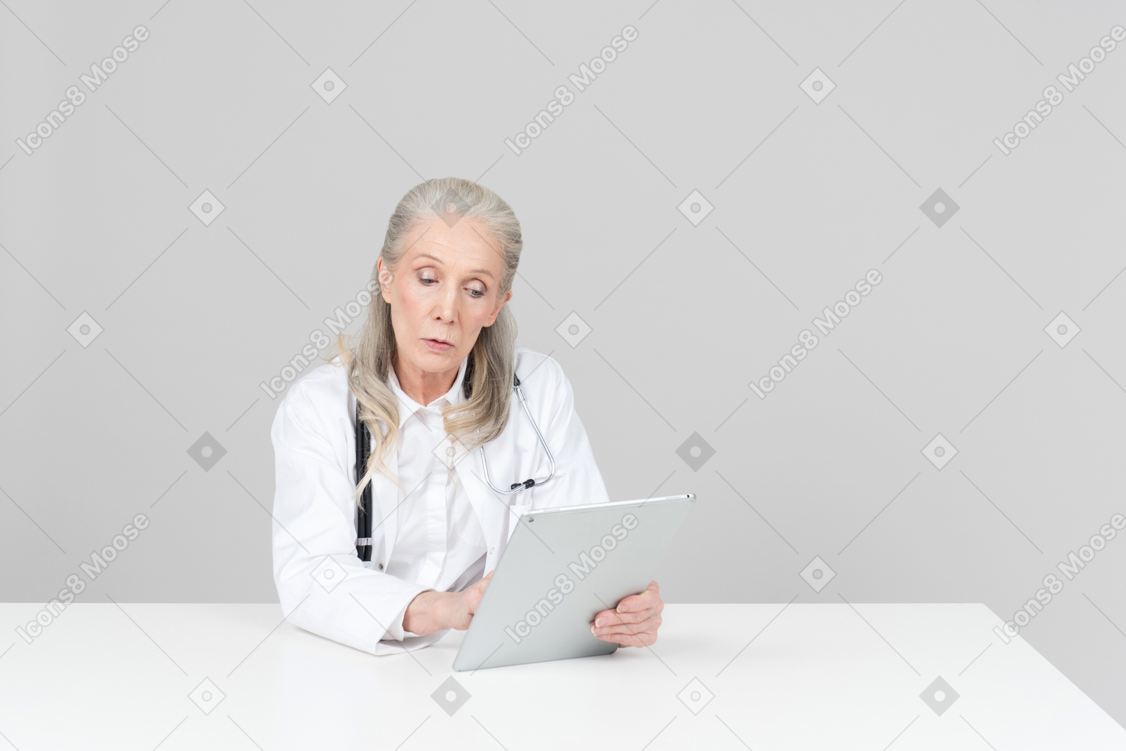 年迈的女医生在数字平板电脑上工作