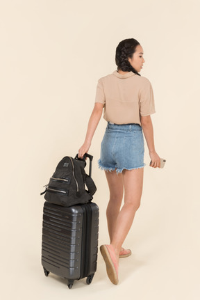 Back view of a young female traveler with suitcase