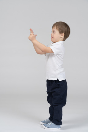 Side view of little boy standing with his hands clasped