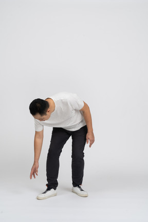 Front view of a man in casual clothes bending down with extended arm