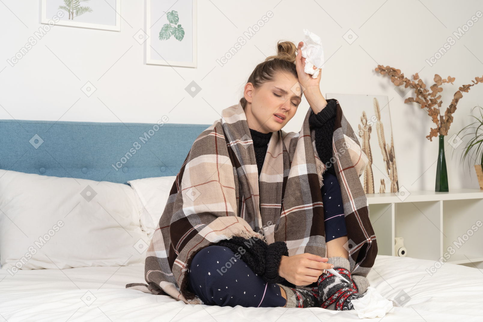 Side view of an ill young lady in pajamas with headache wrapped in checked blanket in bed