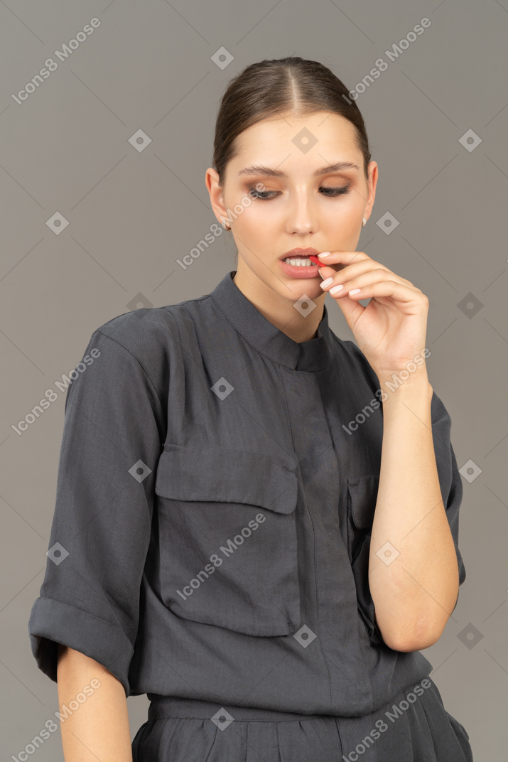 Vista frontal de uma jovem de macacão tomando pílula