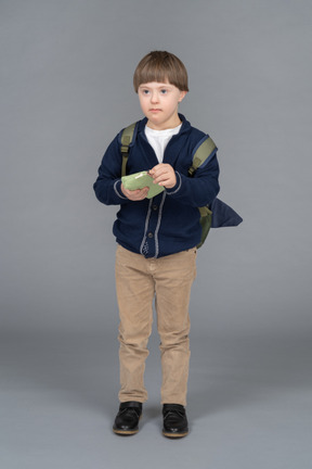Little boy with a backpack holding a pencil case
