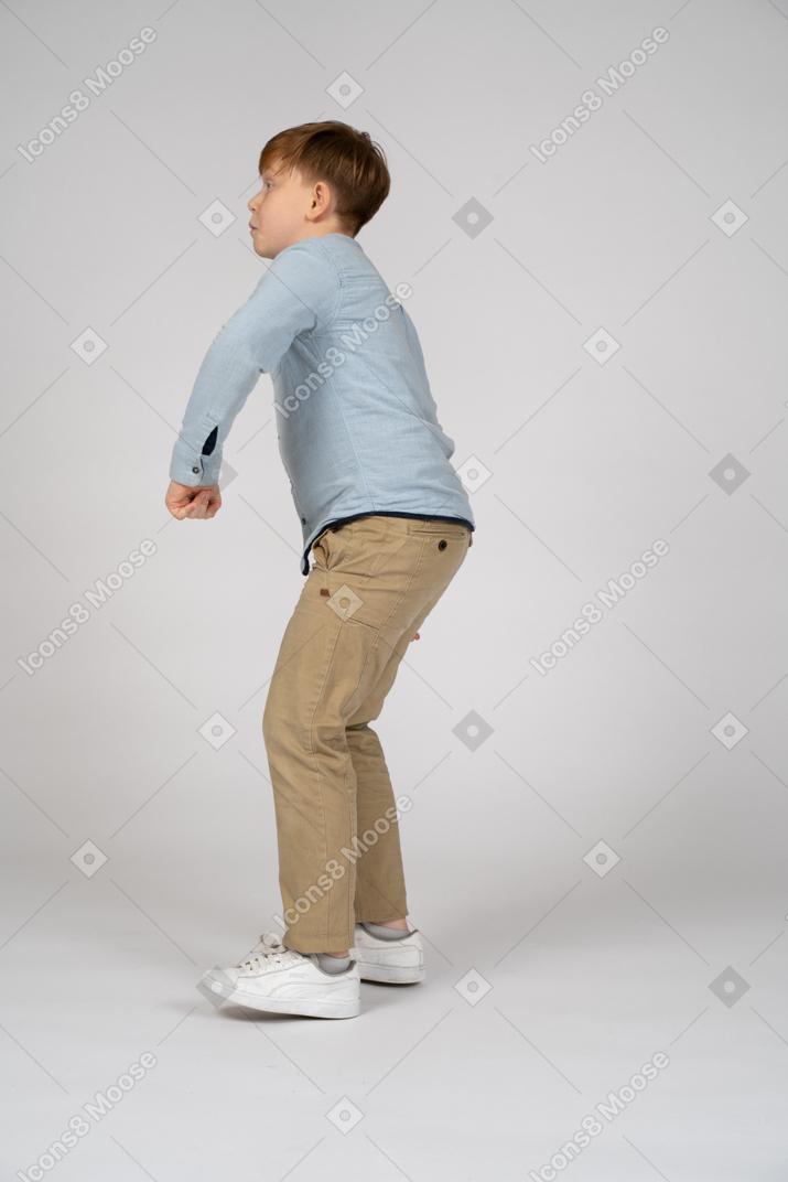 Side view of a boy standing hunched over