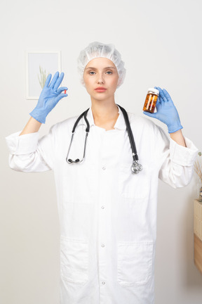 Vista frontal de una joven doctora eligiendo entre pastillas